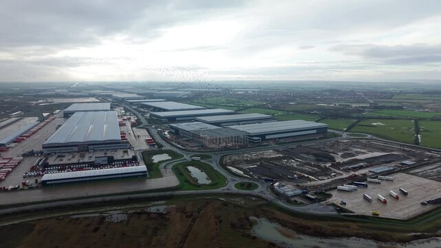 Cinematic bird's eye perspective of a major industrial transport hub in Crick England with warehouses and rail freight links for UK import and export.