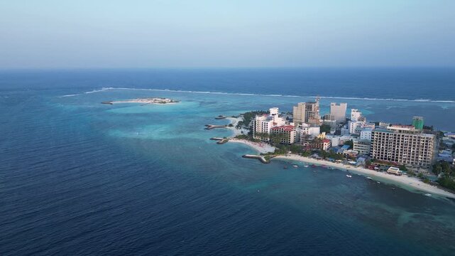 Maafushi, Maldives: Aerial drone footage of waterfront hotels in Maafushi, a local island in Kaafu Atoll of maldives. With orbit motion showing white sand beach and turquoise water