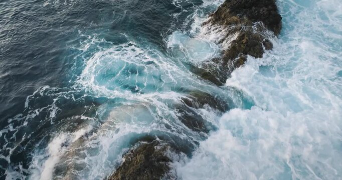 Turquoise ocean waves crashing against dark volcanic rocks