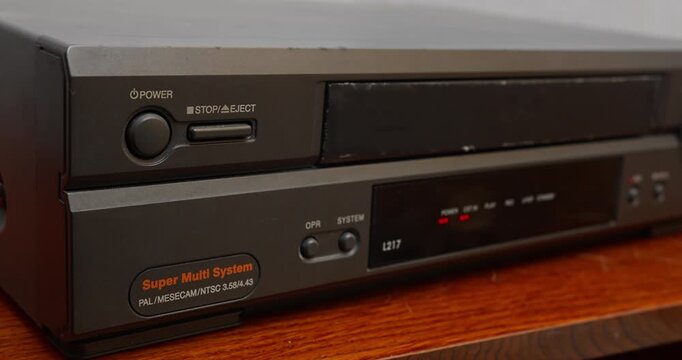 Close-up of VHS tape being ejected from video player. Retro media device and pre-digital entertainment technology