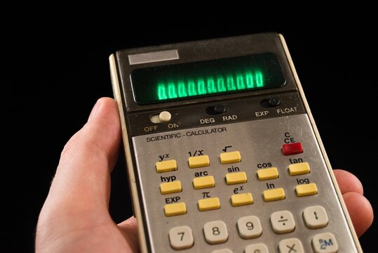 Hand holding vintage retro scientific calculator with green display