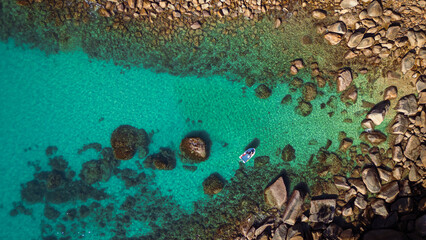 Aerial view of a boat resting on turquoise waters surrounded by rocky shores creating a striking contrast, Mission Beach, Queensland, Australia.