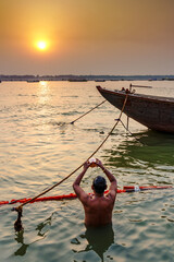 India. Uttar Pradesh state. Varanasi (Benares). A Hindu pilgrim performs the Surya Arghya ritual (sun water offering) in the waters of the sacred Ganges River at sunset