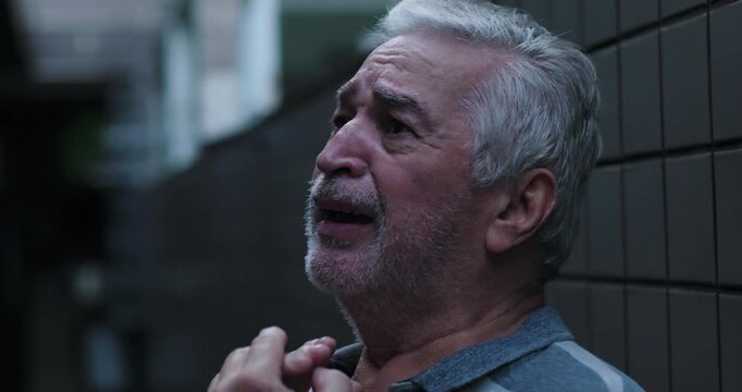 Elderly man outdoors praying with hands together near face expressing desperation faith surrender and plea for divine grace during moment of deep emotional need