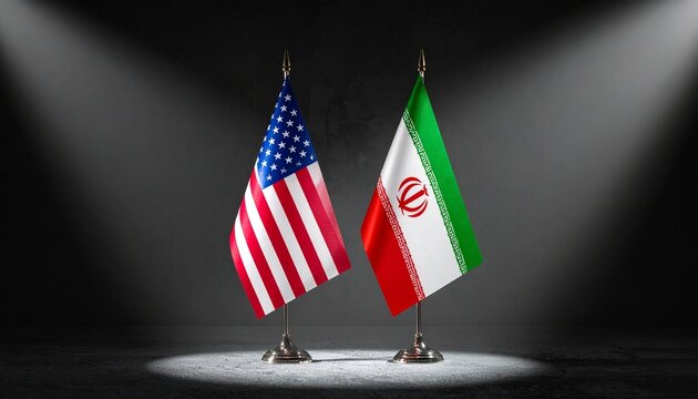 USA and Iran flags under spotlights in dark setting.