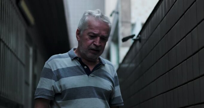 Elderly man walking slowly forward in narrow passage struggling with emotional pain grief exhaustion and heavy burden during darkest period of life