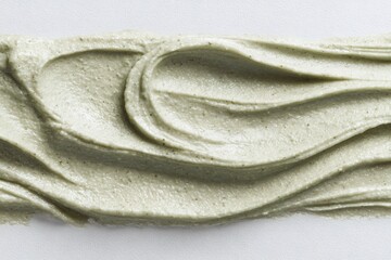 Green clay mask smear texture on white background. Skincare cosmetic product swatch with exfoliating particles for beauty treatment.