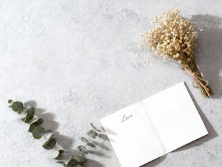 Romantic flat lay with blank card, dried flowers, and eucalyptus. Top view, text space