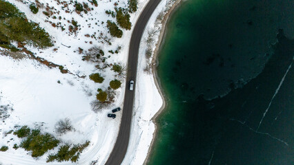 Street in a winter landscape next to a frozen lake

