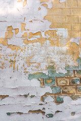 Peeling paint on weathered brick surface texture with cracks and faded colors detail.
