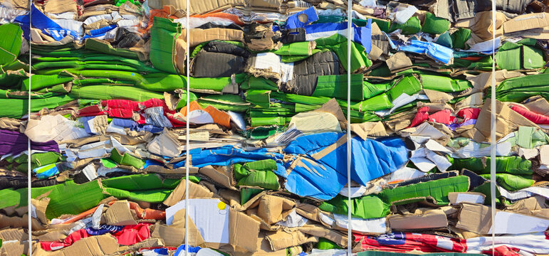 A large colored stack of waste paper from pressed cardboard boxes, sorted and packed for recycling. Garbage sorting, secondary use of resources. Raw materials for the pulp industry. Horizontal photo.