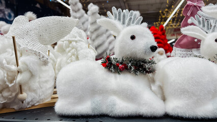 White fluffy reindeer decoration with a festive red berry wreath displayed with other fuzzy winter...