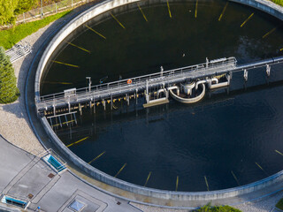 Aerial view of a wastewater treatment plant showing circular settling tanks and water filtration systems integrated into green spaces.