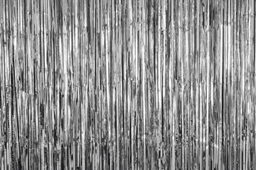 Shiny silver fringe curtain background with vertical metallic strands reflecting light.