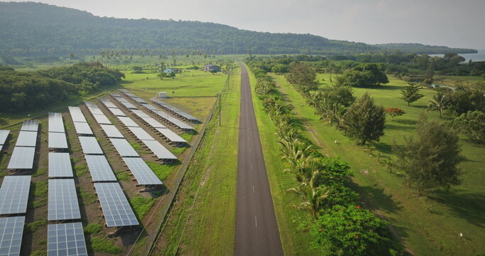 Fiji, Port Villa: solar electric panels along the road, surrounded by green fields and distant hills on Efate Island. Sustainable energy wild nature landscape. Aerial view drone flight