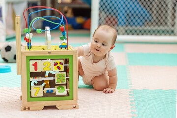 Baby playing with wooden educational activity cube at daycare