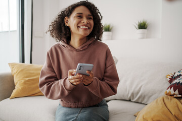 Cheerful Woman Sits On Comfortable Couch Mapping Out Travel Plans Surrounded By Natural Elements...
