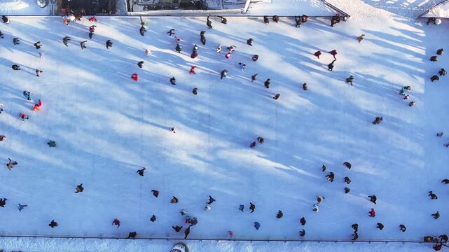 Ice skating occurs outdoors with many enjoying the winter fun