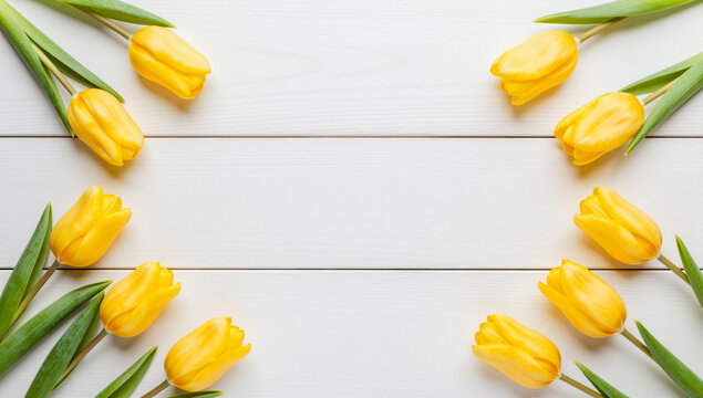 Yellow tulips on white wooden background spring flat lay top view floral decoration copy space feminine greeting card template rustic table aesthetic