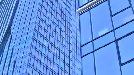 Obraz premium A modern tall building made of steel and glass, housing offices and financial institutions. Glass wall on the facade of the building.