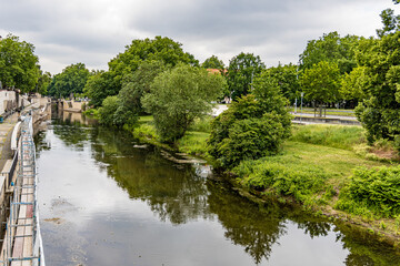 Fototapeta premium A river with a bridge and trees on both sides in Hanover Germany. The water is calm and the trees are green