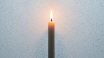Single lit candle with warm flame on textured gray background symbolizing calmness and serenity in a peaceful atmosphere