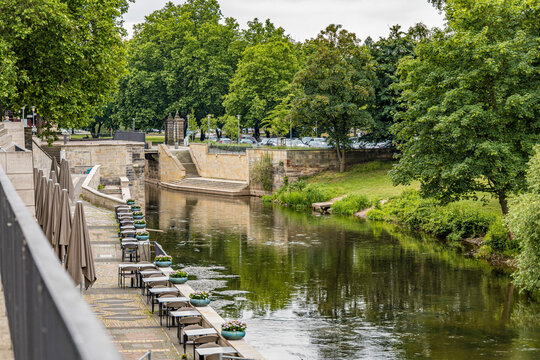 A river with a bridge and trees on both sides in Hanover Germany. The water is calm and the trees are green
