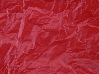 Fototapeta premium Close-up of crumpled red plastic texture background. Ideal for abstract background, industrial themes, or environmental concept