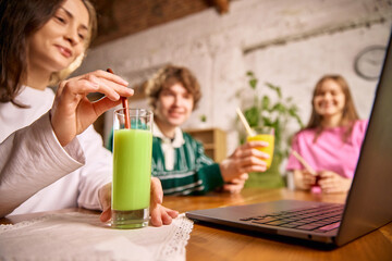 Colleagues enjoying fresh juices together while working on laptops. Concept of healthy lifestyle, social connection, teamwork, balanced nutrition, positive energy and modern home work environment.