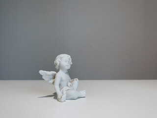 White ceramic angel figurine on white background for design. Faith, symbols, and traditions.