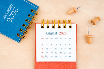 August 2026 desk calendar with wooden thumbtack on brown paper.