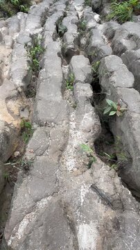 Full frame texture of cracked grey stone floor with natural eroded paths and crevices