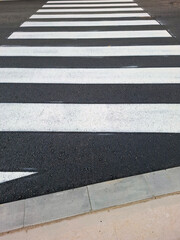 Fototapeta premium New pedestrian crossing markings appear on recently asphalted road in city area
