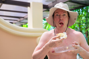Shocked Scandinavian Tourist Man Eating Durian Outdoors with Tropical Leaves Background