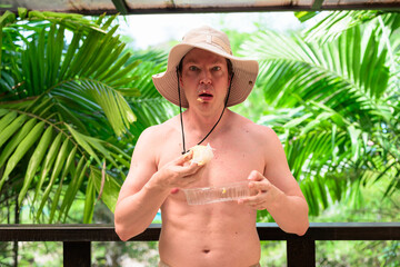 Scandinavian Tourist Man Eating Durian Outdoors with Tropical Leaves Background