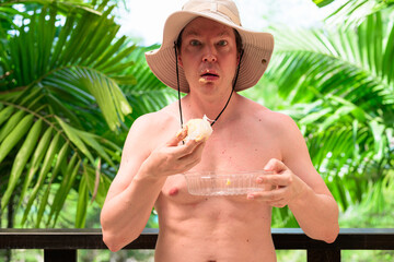 Scandinavian Tourist Man Eating Durian Outdoors with Tropical Leaves Background