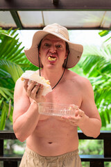 Scandinavian Tourist Man Eating Durian Outdoors with Tropical Leaves Background