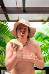 Scandinavian Tourist Man Eating Durian Outdoors with Tropical Leaves Background