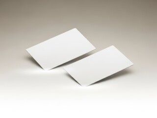 Two blank white business cards are placed overlapping on a plain surface.