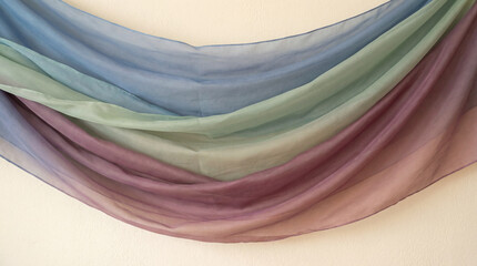 A sheer fabric gracefully drapes, showcasing a smooth transition through shades of blue, green, and rose, creating a soothing and ethereal gradient effect.