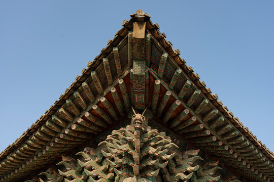 Ornate roof of a traditional building with intricate details, featuring a carved dragon motif against the sky.