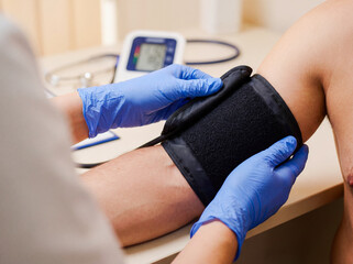 Doctor hands adjusting blood pressure cuff on patient arm first aid medical diagnostic healthcare professional blue nitrile gloves clinic checkup background copy space hypertension