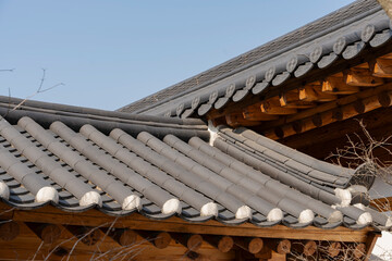A traditional roof with gray tiles and wooden beams, a showcase of architectural heritage under a blue sky.