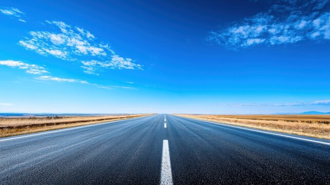 A long, straight road stretching into the distance with a clear blue sky above and a few scattered clouds.
