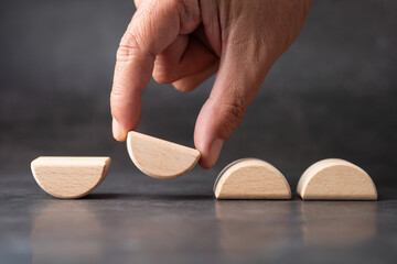 Hand flipping a wooden semicircle block to represent role transition, repositioning, and strategic change in business