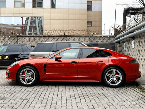  Hybrid Porsche Panamera 4S orange color parked at the city street. Orange car Porsche Panamera 4S on parking lot. The modern exterior of a premium German premium car. 