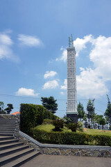 Fototapeta premium The tall mosque tower with modern white architecture stands firmly in the neatly maintained mosque garden area, with a backdrop of blue skies and bright clouds. 