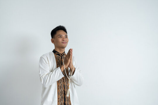 Asian Man in Islamic Attire Standing with Hands Joined, Peaceful Spiritual Greeting