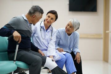 Obraz premium A doctor is helping an elderly man with his leg. The doctor is wearing a white coat and the man is wearing a gray sweater. A man suffered a broken leg. The scene is set in a hospital room.