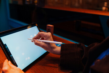 Close-up of woman's hands using stylus on digital tablet, highlighting precision, user interaction, and the tactile engagement of digital tools in creative or professional tasks.